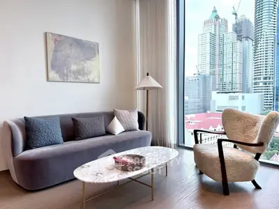 Modern living room with stylish furniture and city view, featuring a cozy sofa and elegant armchair.