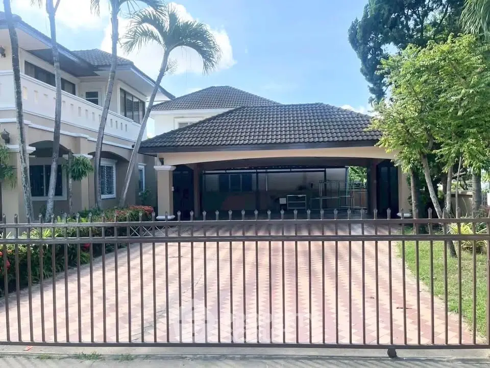 Spacious suburban home with gated driveway and lush greenery, perfect for family living.