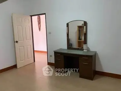 Spacious bedroom with elegant vanity and open door to adjacent room.