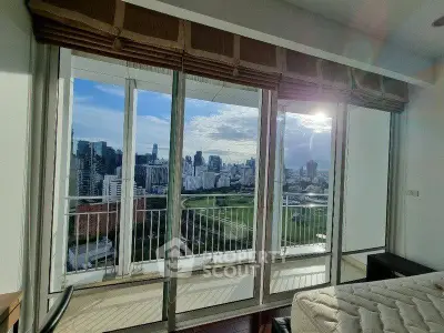 Stunning cityscape view from a modern high-rise apartment with floor-to-ceiling windows and balcony access.