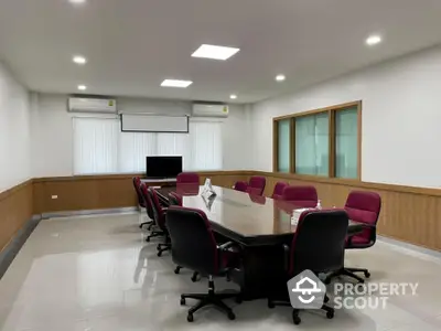 Spacious and modern conference room with a large table, comfortable chairs, and state-of-the-art presentation equipment, ideal for business meetings.