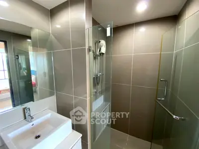 Modern bathroom with sleek shower and stylish sink in contemporary apartment.