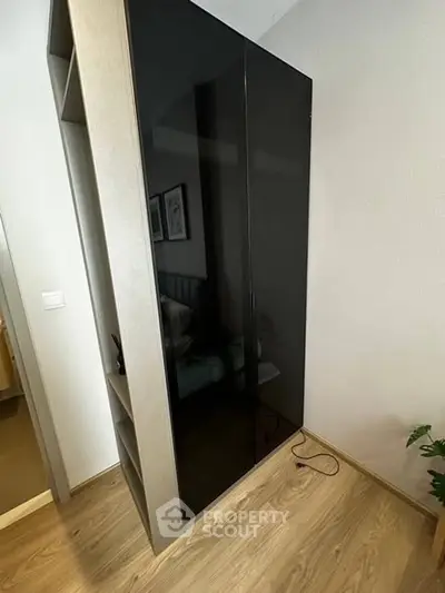 Modern bedroom with sleek black wardrobe and wooden flooring