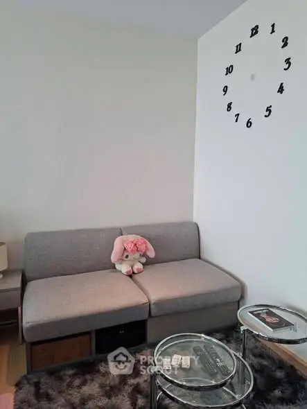 Cozy living room with modern gray sofa and stylish wall clock, perfect for relaxation.