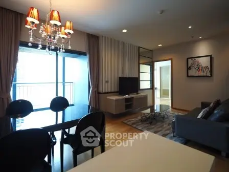 Modern living room with elegant chandelier and balcony view in a stylish apartment.