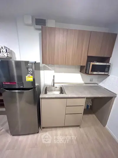 Modern compact kitchen with stainless steel fridge and microwave