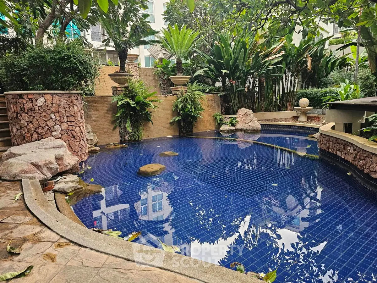 Luxurious outdoor pool surrounded by lush greenery in a serene residential setting.