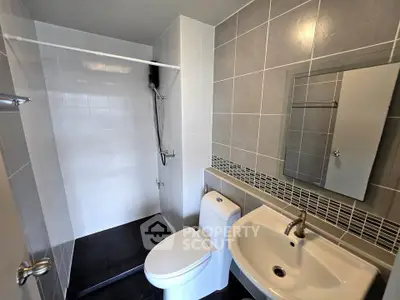 Modern bathroom with sleek design, featuring a shower, toilet, and sink with a stylish mirror.
