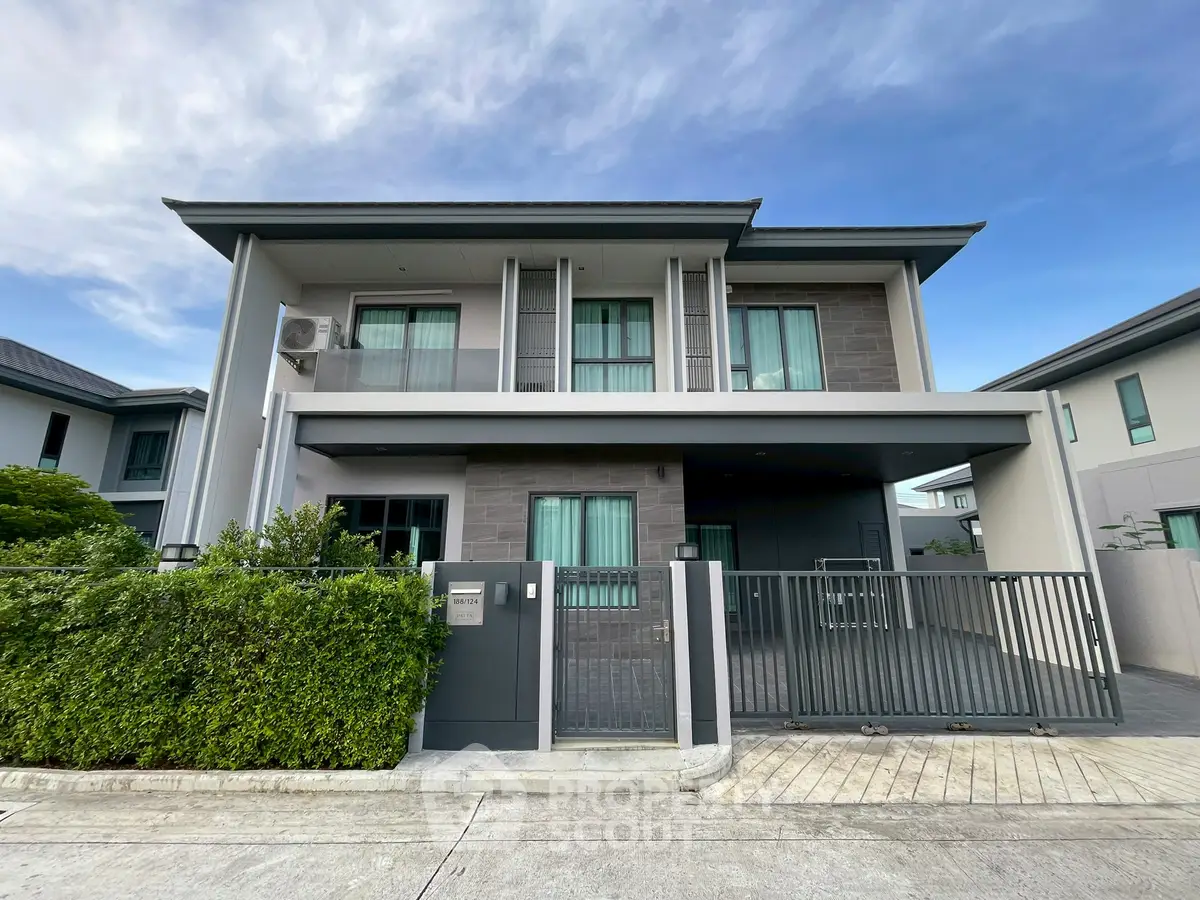 Modern two-story house with sleek design and gated entrance in suburban neighborhood.