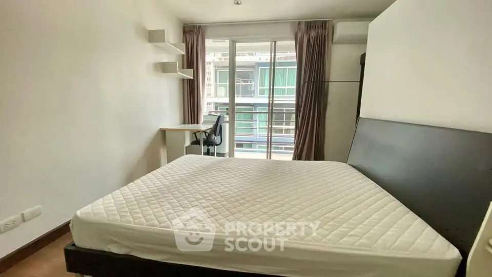 Modern bedroom with large window and study desk, offering natural light and a cozy atmosphere.