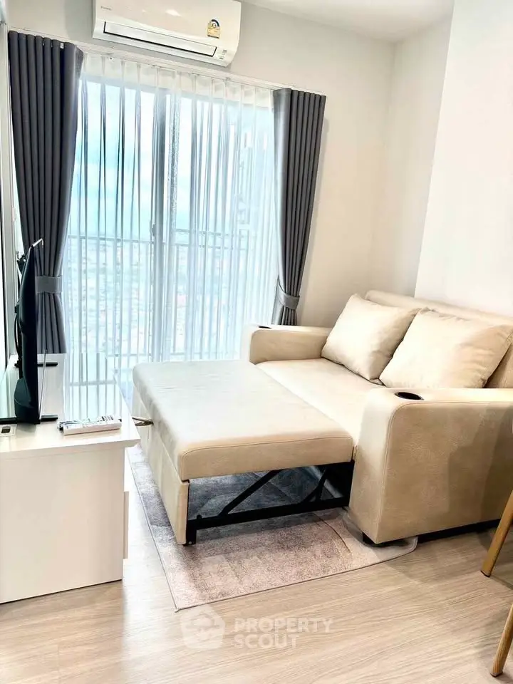 Modern living room with sofa bed and air conditioning, featuring a bright window view.