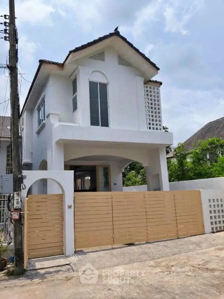 Charming two-story white house with modern design and wooden gate in a serene neighborhood.