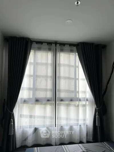 Cozy bedroom with large window and elegant curtains, perfect for natural light lovers.