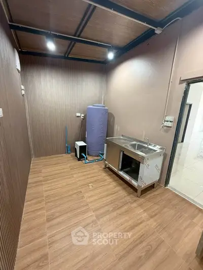 Compact kitchen area with stainless steel sink and wooden flooring, ideal for efficient space utilization.