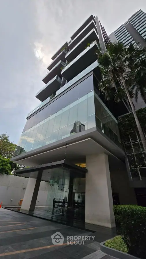 Modern high-rise building with sleek glass facade and lush greenery