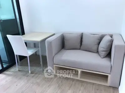 Cozy modern living room with compact sofa and dining table in bright apartment.