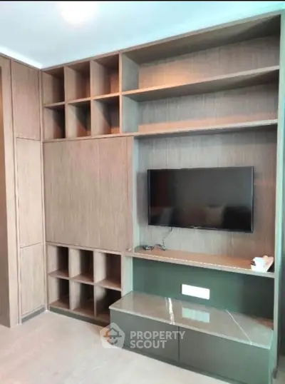 Modern living room with built-in wooden shelves and mounted TV, perfect for stylish urban living.