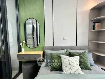 Modern bedroom with stylish decor and green accents, featuring a cozy bed and elegant mirror.