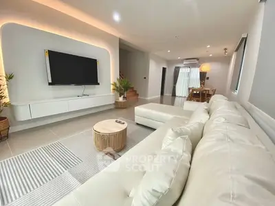 Modern living room with sleek design and wall-mounted TV, featuring cozy white sofa and stylish decor.
