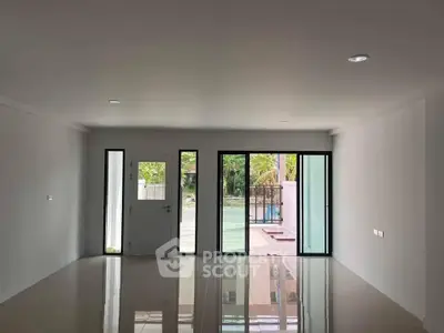 Spacious modern living room with large windows and glossy tiled floor, offering abundant natural light.
