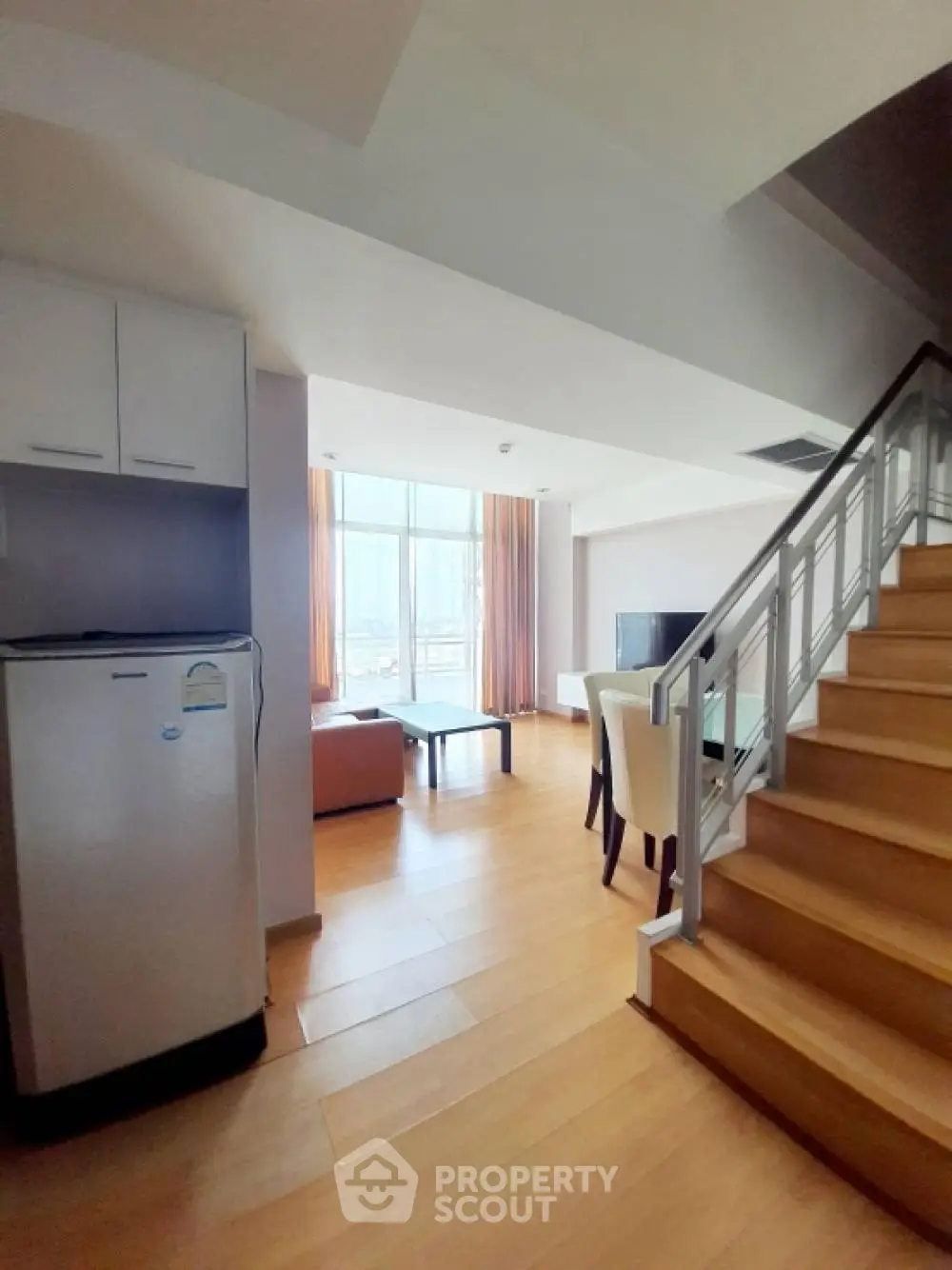 Spacious duplex living room with modern furniture and large windows offering natural light.
