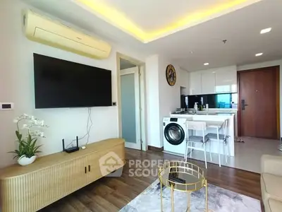 Modern living room with open kitchen and washing machine, featuring stylish decor and wooden flooring.