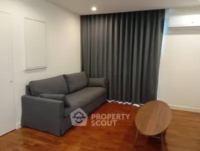 Modern living room with gray sofa, wooden floor, and stylish coffee table.