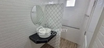 Modern bathroom with stylish white tiles and round mirror