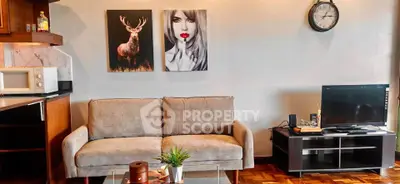 Stylish living room with modern decor, featuring a cozy sofa, wall art, and entertainment setup.