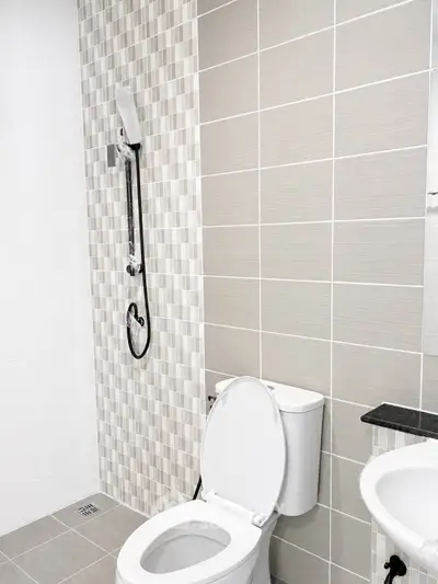 Modern bathroom with sleek tiles and contemporary fixtures, featuring a shower and toilet.