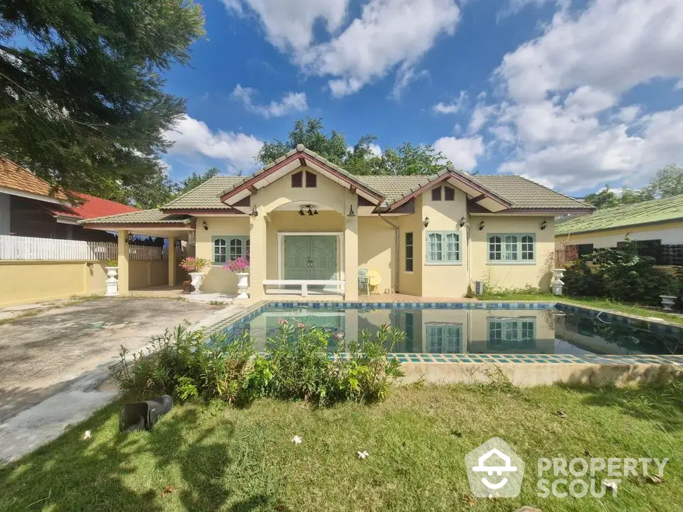 Charming single-story home with pool and lush garden under blue skies.