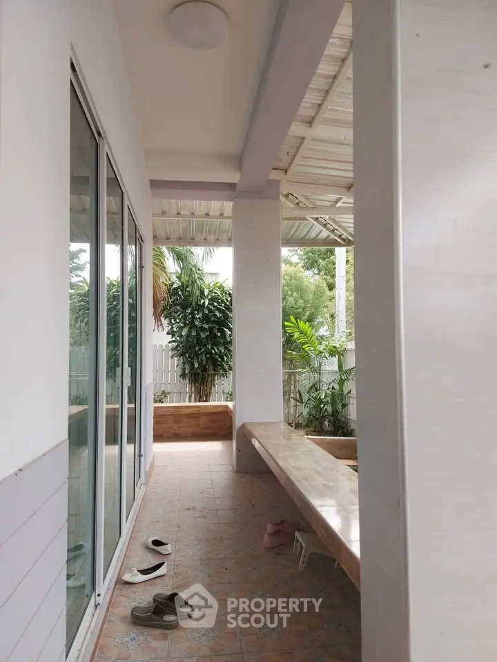 Charming covered patio with tiled flooring and lush garden view, perfect for relaxation.