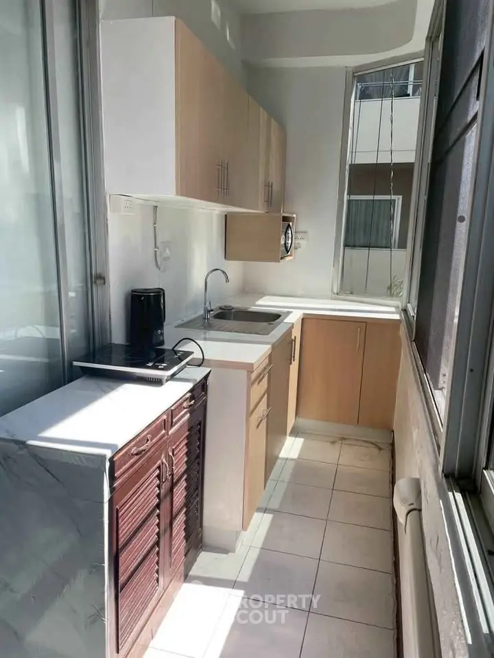 Bright and compact kitchen with modern cabinetry and ample natural light, perfect for efficient cooking.