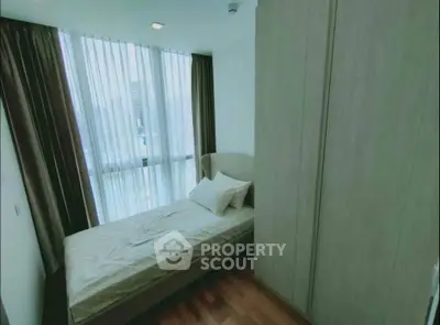 Cozy bedroom with large window and modern furnishings in a stylish apartment.
