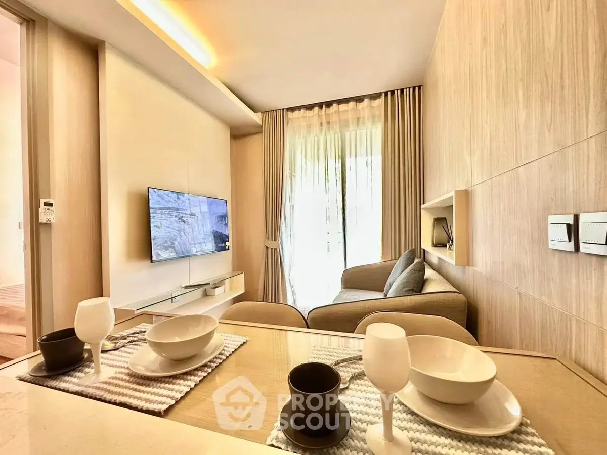 Modern living room with cozy sofa, wall-mounted TV, and elegant dining setup in a bright apartment.