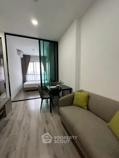Modern apartment interior with cozy living room and bedroom separated by glass wall, featuring stylish decor.