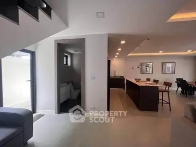 Modern open-plan living area with sleek kitchen and dining space, featuring contemporary design and ample natural light.