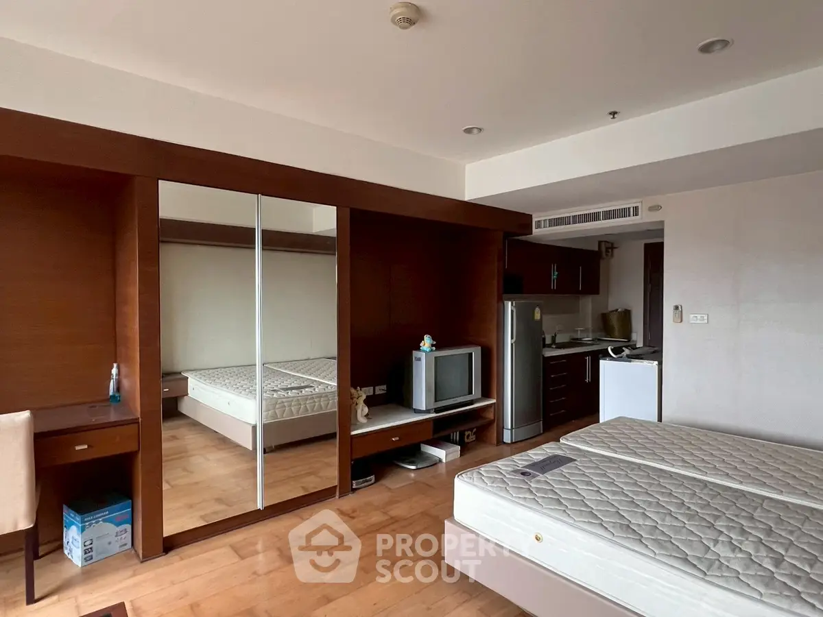 Spacious bedroom with mirrored wardrobe and kitchenette, ideal for modern living.