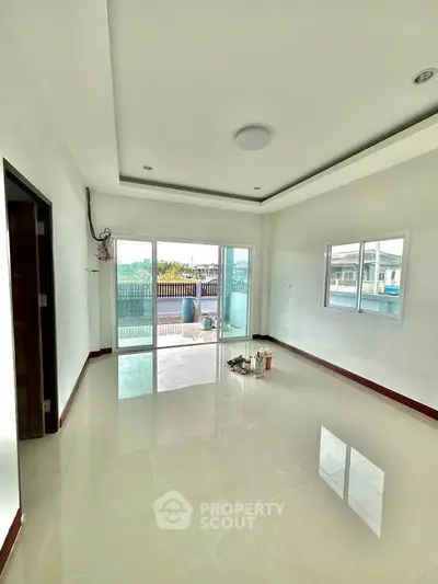 Spacious living room with glossy tiled floors and large sliding glass doors leading to a balcony.