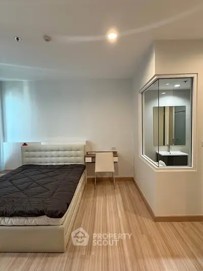 Modern bedroom with sleek design and large window, featuring a comfortable bed and stylish wooden flooring.