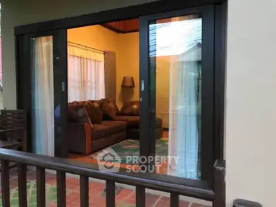 Charming living room with cozy sofa and warm lighting viewed through sliding glass doors.