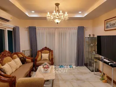 Elegant living room with chandelier, classic furniture, and large windows for natural light.