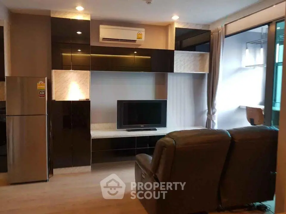 Modern living room with sleek black cabinetry, TV, and comfortable seating in a stylish apartment.