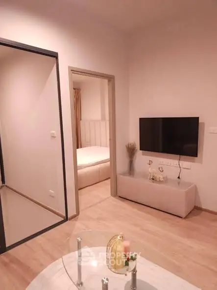 Modern living room with wall-mounted TV and view into cozy bedroom