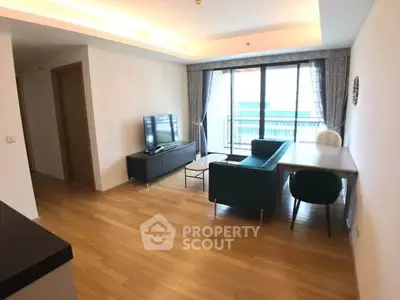 Spacious modern living room with wooden flooring and large windows leading to a balcony.