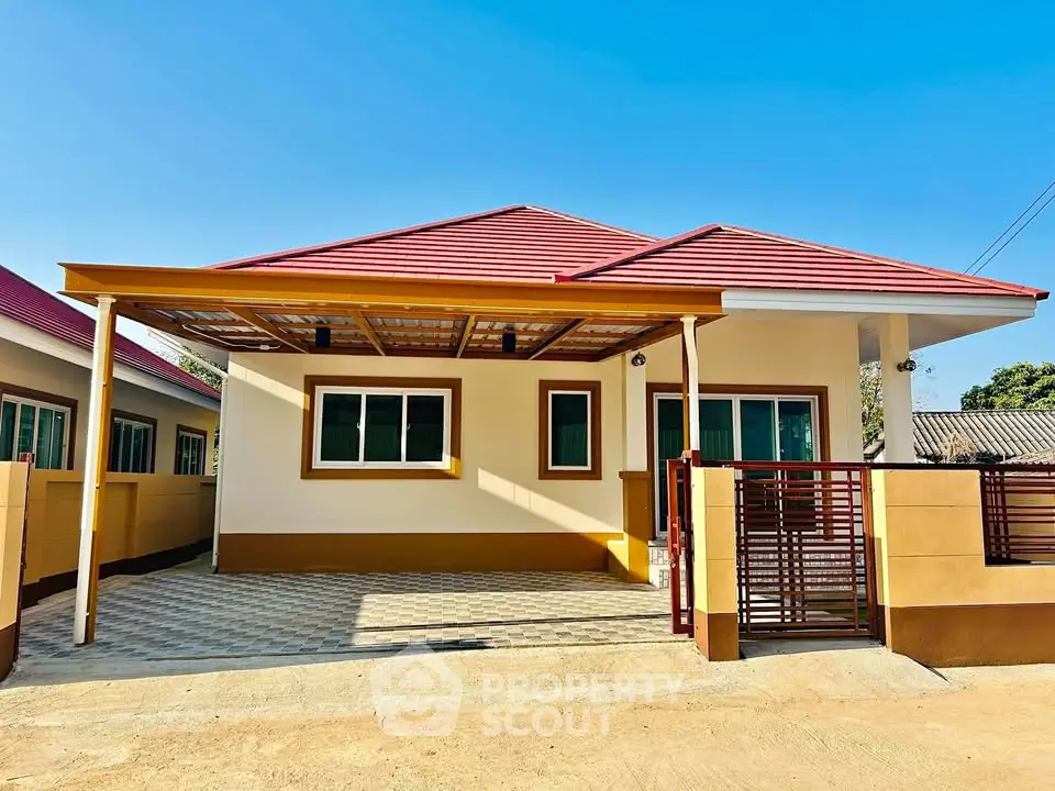 Charming single-story house with red roof and spacious driveway under clear blue sky.