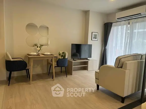 Modern living room with stylish furniture and natural light, featuring a cozy dining area and sleek TV setup.