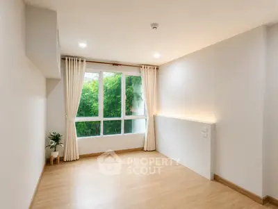 Bright and airy room with large window and wooden flooring, perfect for a cozy living space.