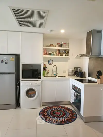 Modern kitchen with white cabinets, washing machine, and colorful rug