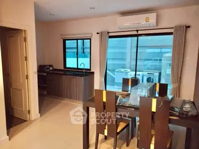 Modern dining area with sleek kitchen and large windows, featuring contemporary furniture and appliances.